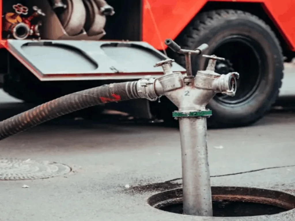 Professional, high-pressure pumping equipment connected to an underground cesspool via a manhole for maintenance and cleaning services.